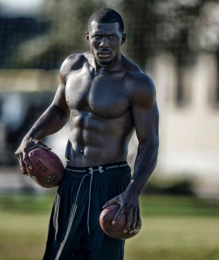 a shirtless man holding a football in his hands