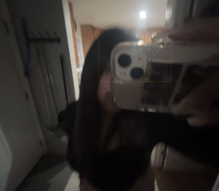 a blurry image of a person taking a selfie with a camera in the mirror