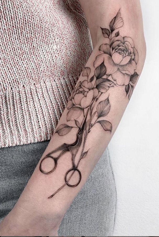 a woman's arm with scissors and flowers on it