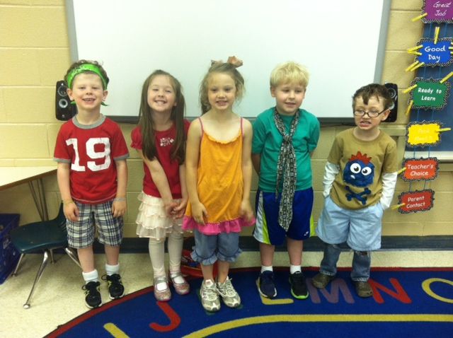 five children are standing in front of a whiteboard