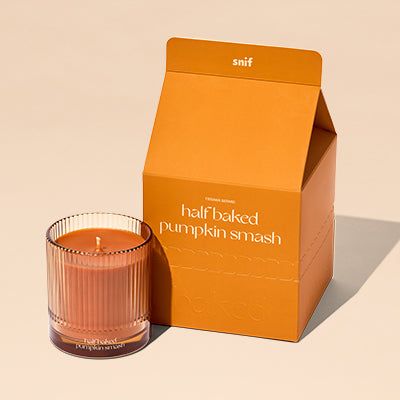 an orange box next to a candle on a white surface with a light brown background