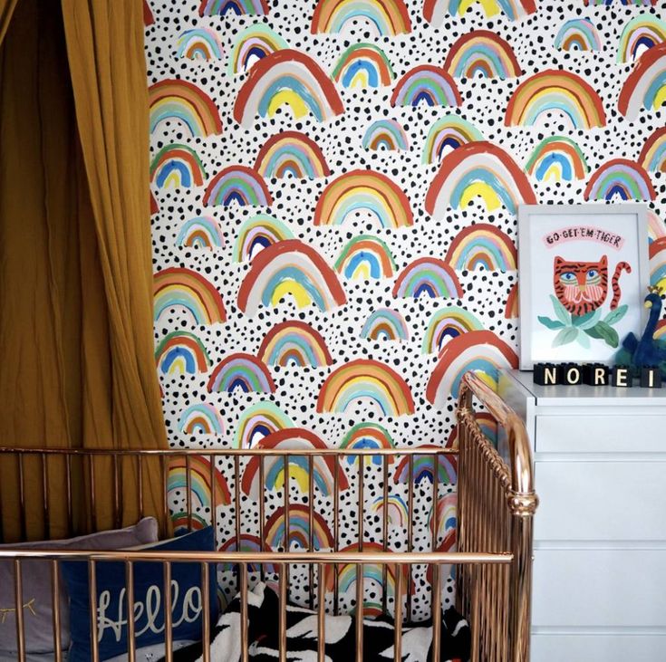 a baby crib next to a colorful wallpaper