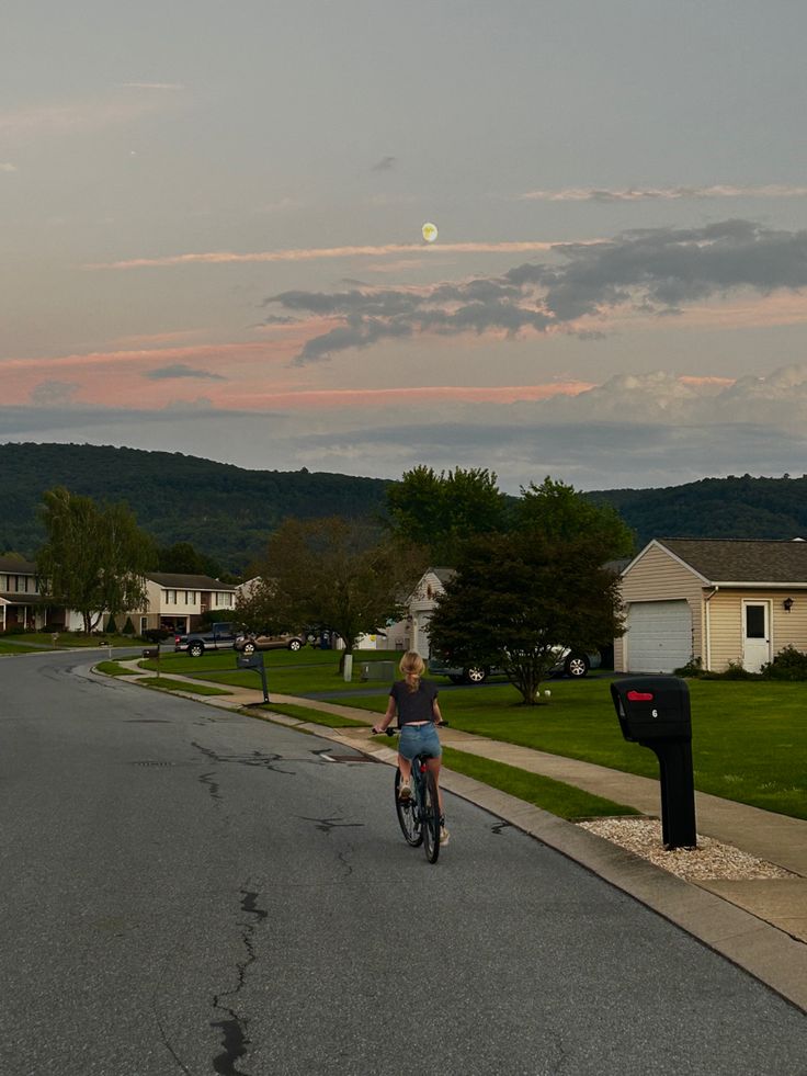 a person riding a bike down the middle of a street with houses in the background