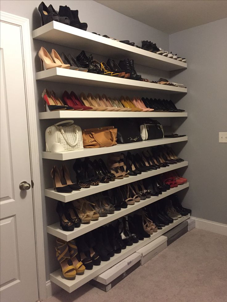 a closet filled with lots of shoes and purses on shelves next to a door