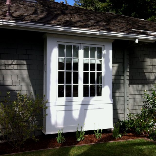 a white window on the side of a gray house