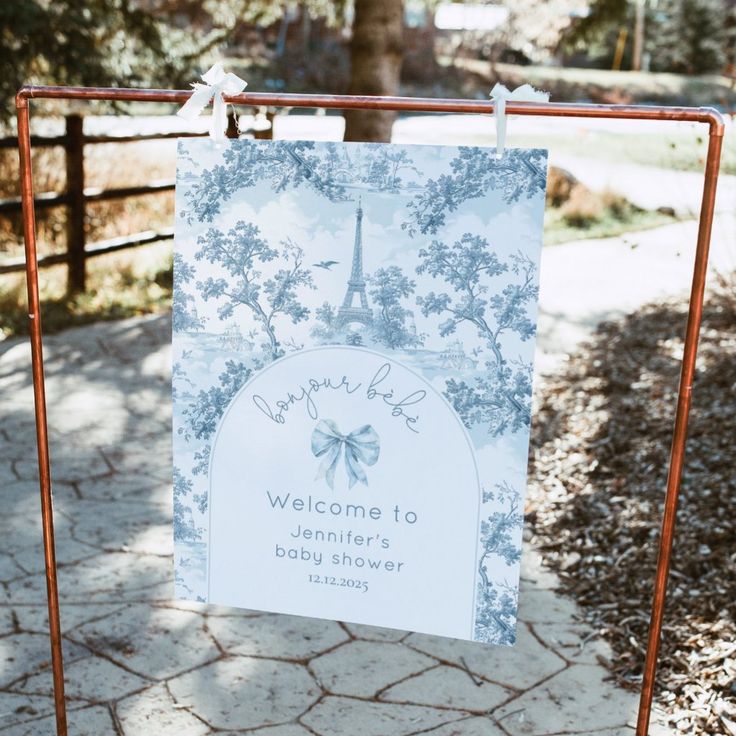 a welcome sign is hanging on a metal frame in front of the eiffel tower