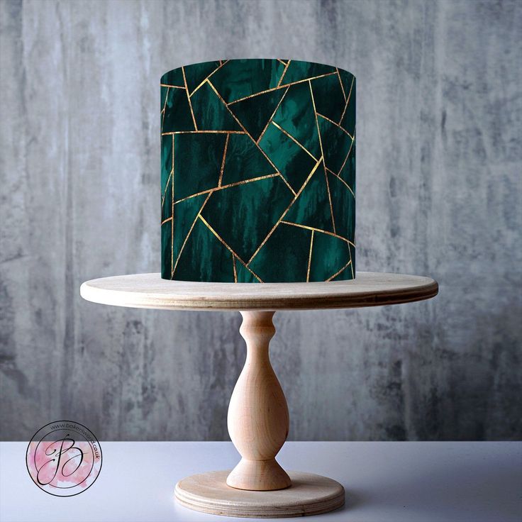 a green and gold cake sitting on top of a wooden stand next to a wall