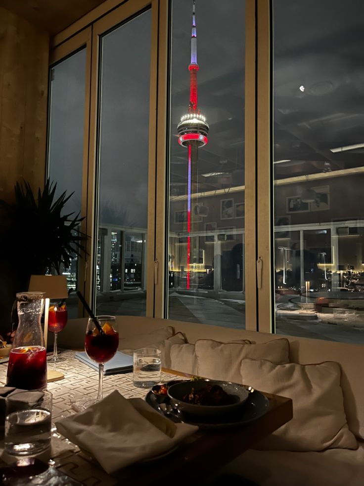 a table with food and drinks on it in front of large windows that look out onto the city