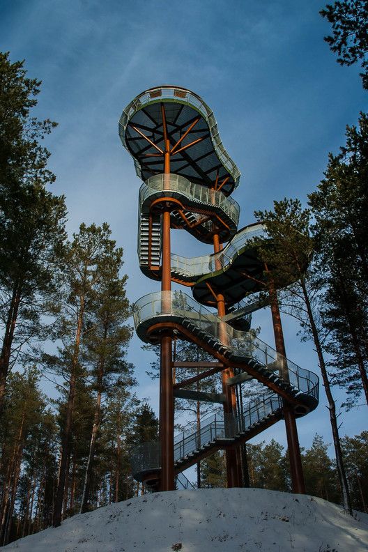 a large metal spiral staircase in the middle of trees