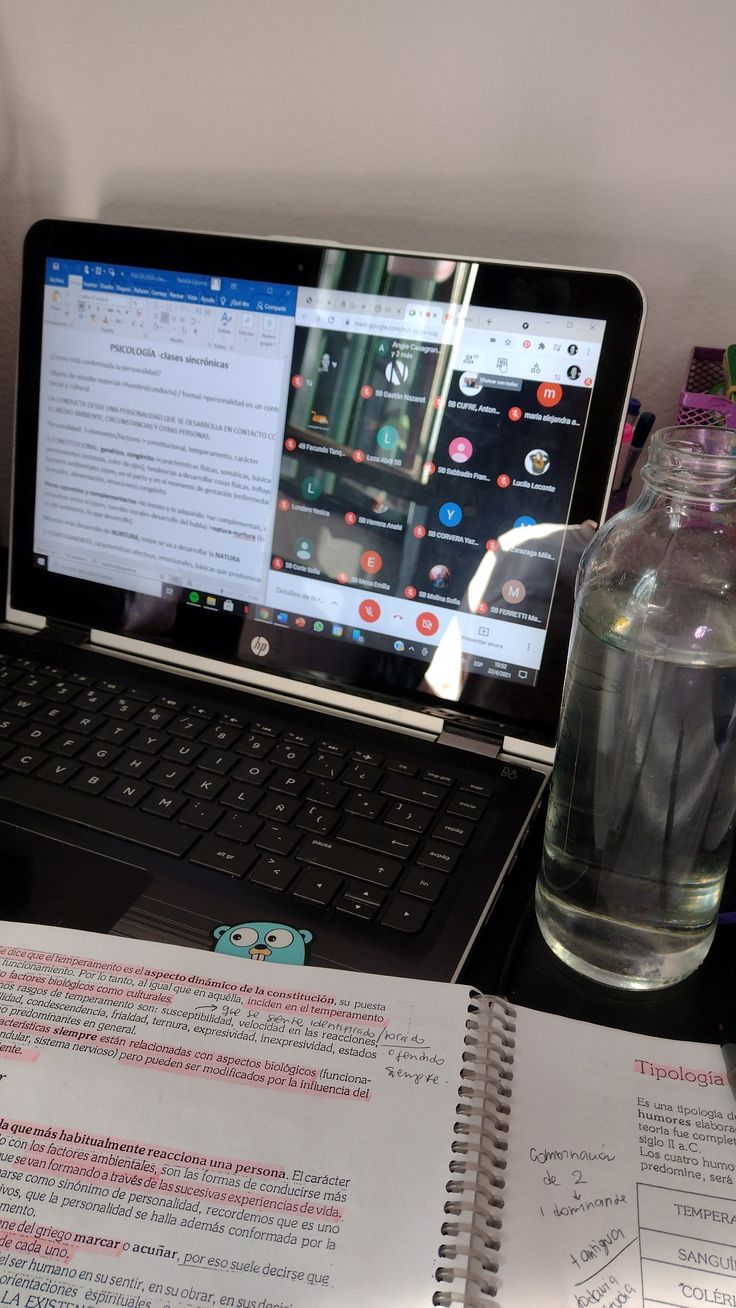 an open laptop computer sitting on top of a desk next to a bottle of water