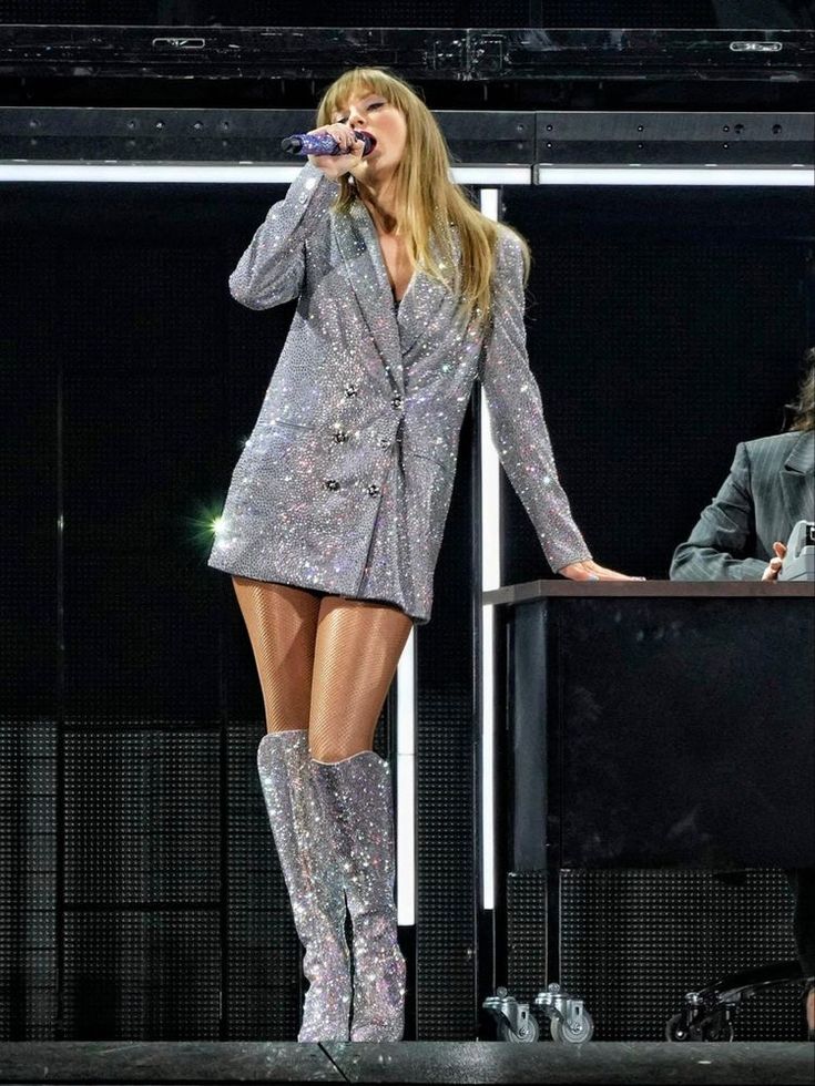 lady in silver dress and boots on stage with microphone