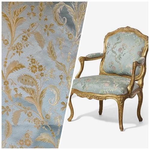 an old chair is next to a wallpaper with gold and blue flowers on it