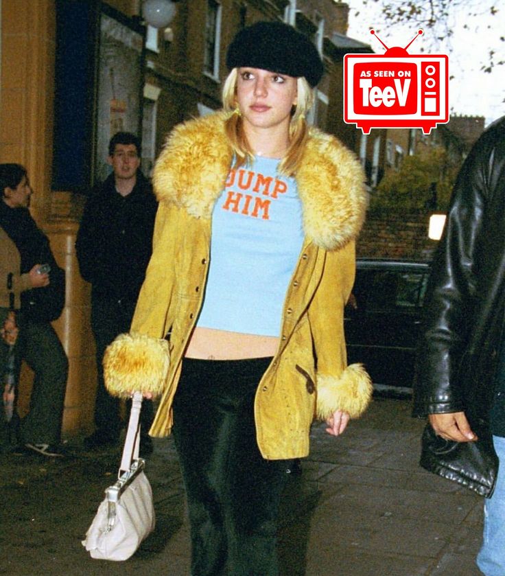 a woman walking down the street with a fur coat over her shoulders and handbag in her other hand