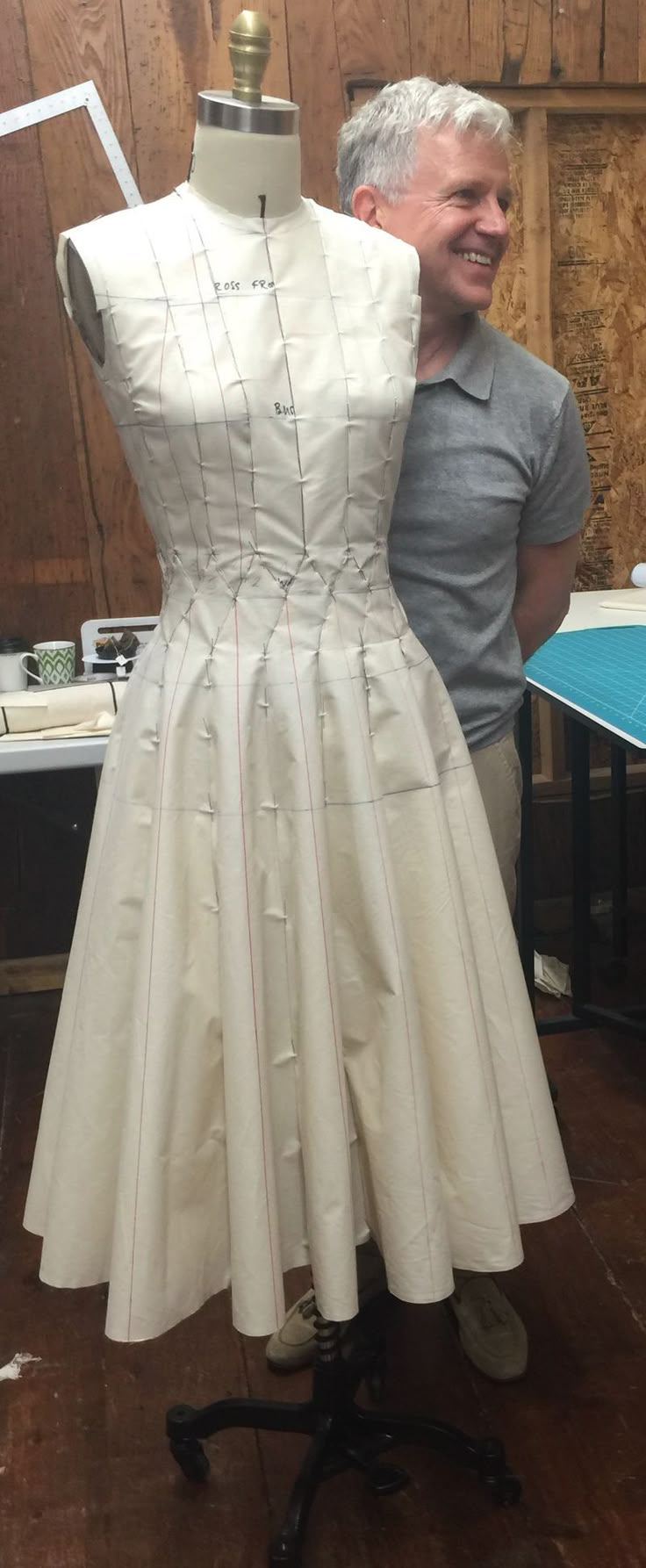 a man standing next to a white dress on a mannequin's head