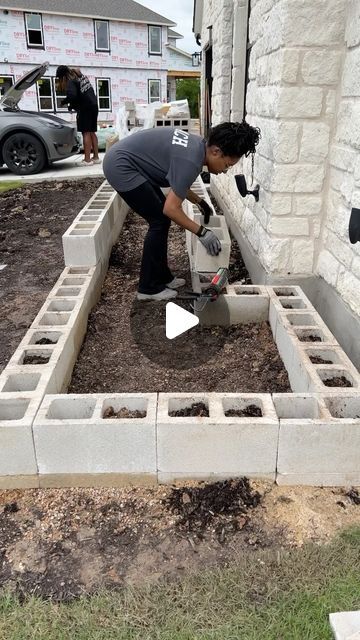 a man is working in the garden with cement blocks and shovels to plant flowers