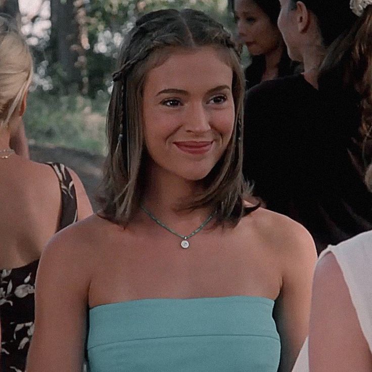 a woman in a blue strapless dress standing next to other women and smiling at the camera