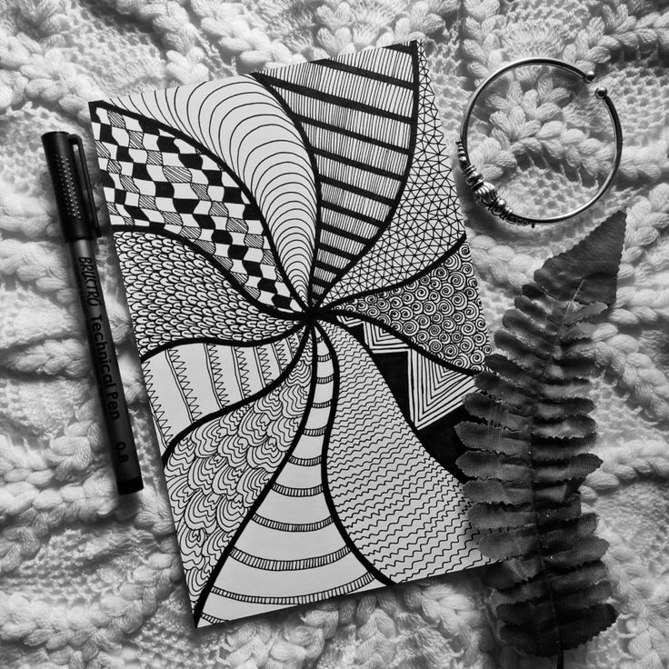 a black and white photo of a spiral notebook with a pen next to it on a blanket