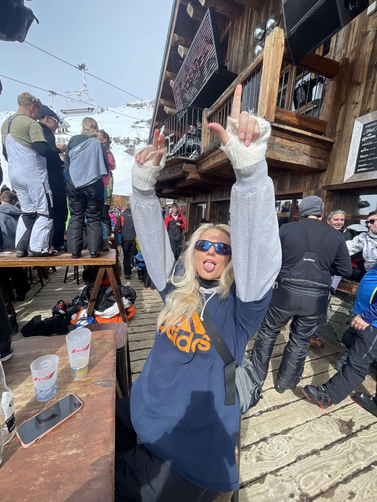 a woman with her hands up in the air at a ski slope resort on a sunny day