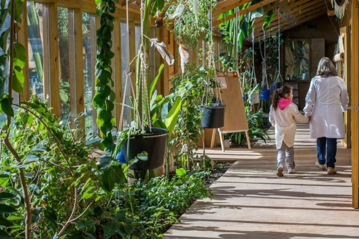 a woman and child walking down a walkway in a greenhouse