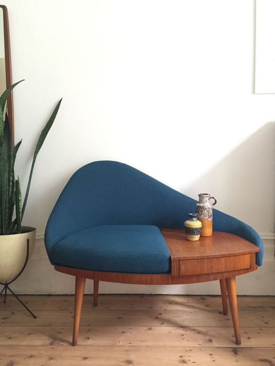 a blue couch sitting on top of a wooden table next to a potted plant