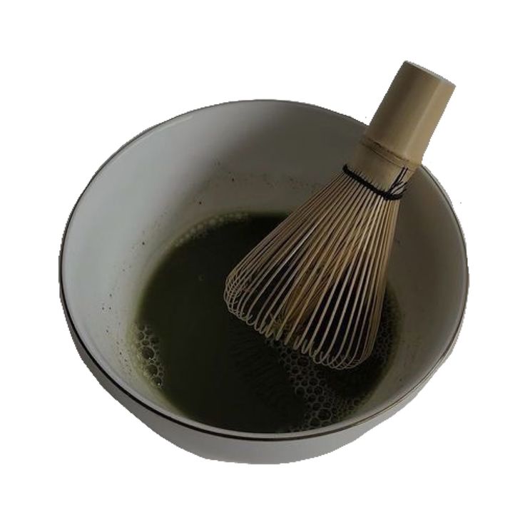 a whisk in a bowl filled with green liquid