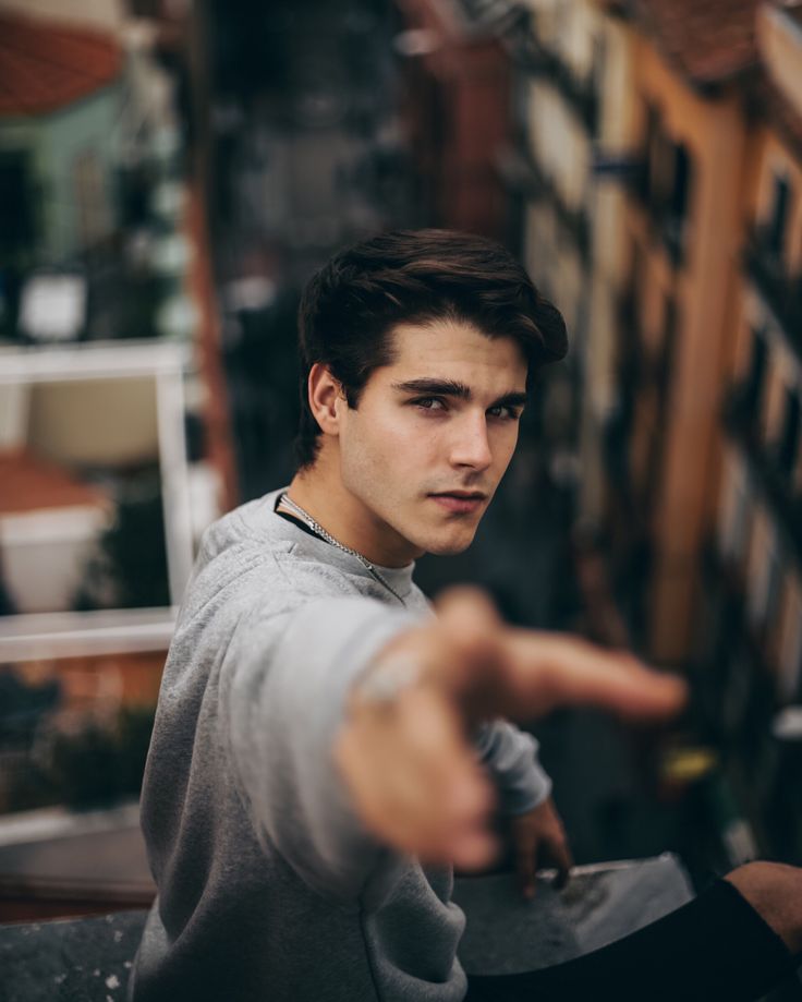 a young man pointing at something in the air with his hand on top of him