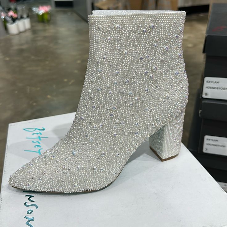 The Cady Is A Disco-Ready Bootie That Will Take Any Outfit You Wear To The Next Level. These Ankle Boots Feature A Pointed Toe And A Study, Block Heel And Are Fully Decked Out With Pearl Rhinestones. Glitz And Glam Have Never Looked Better. Pearl Embellished Booties Side Zipper Closure Textile Lining Betsey Blue Sole 3.5 Inch Heel Height 5.5 Inch Shaft Height White Closed Toe Party Boots, White Block Heel Boots For Evening, White Closed-toe Party Boots, Evening White Block Heel Boots, White Synthetic Boots For Formal Occasions, White Block Heel Boots For Formal Occasions, White Formal Boots With Block Heel, White Rhinestone Boots With Round Toe, White Low Heel Party Boots