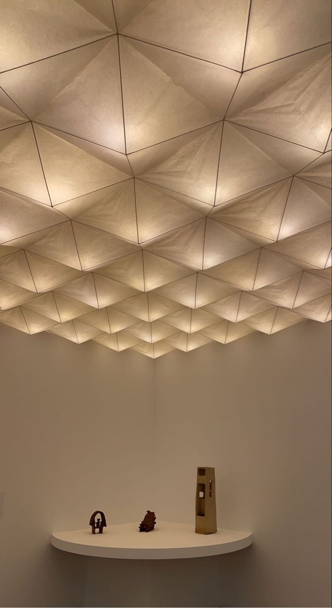 a room with white walls and ceiling that has suspended lights above the table in front of it