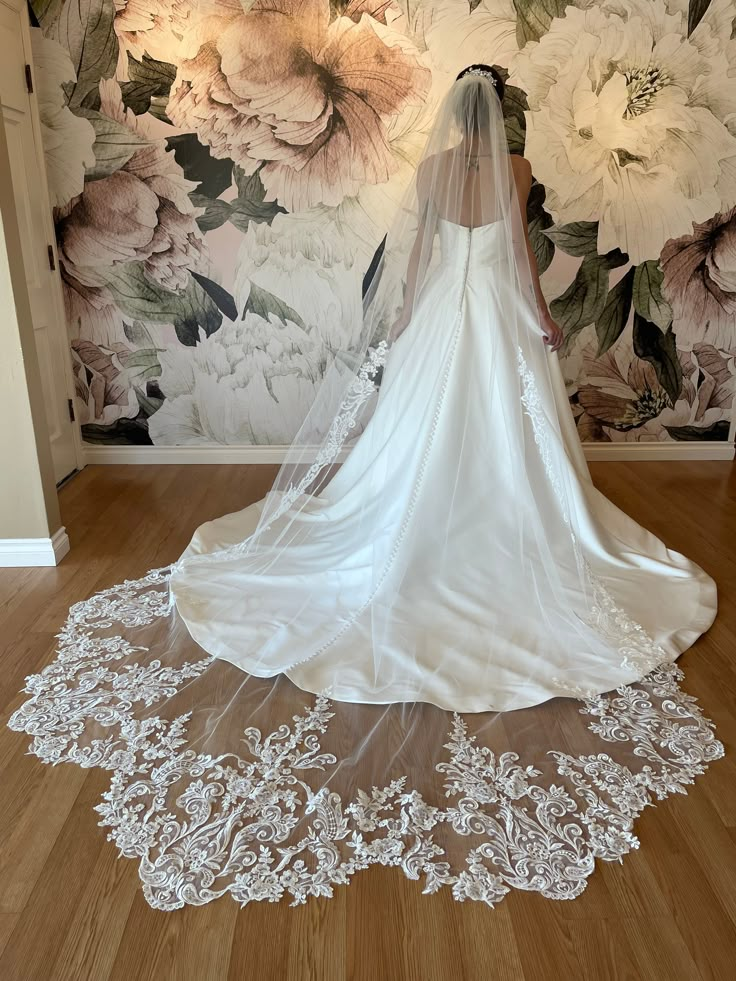 the back of a bride's wedding dress in front of a floral wallpaper