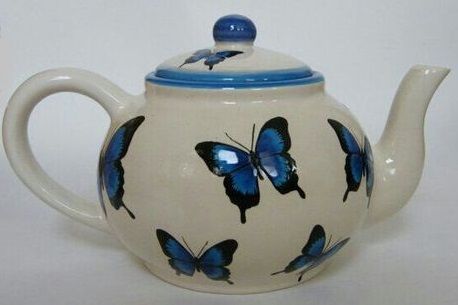 a tea pot with blue butterflies painted on it