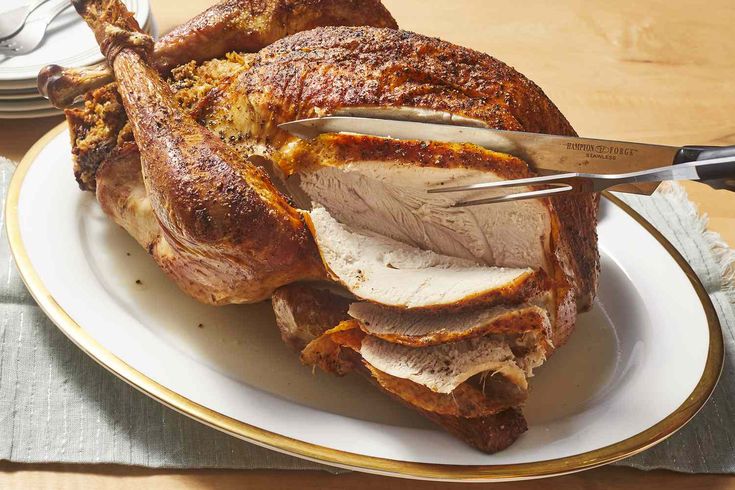 a large roasting turkey on a plate with a knife and fork in the middle