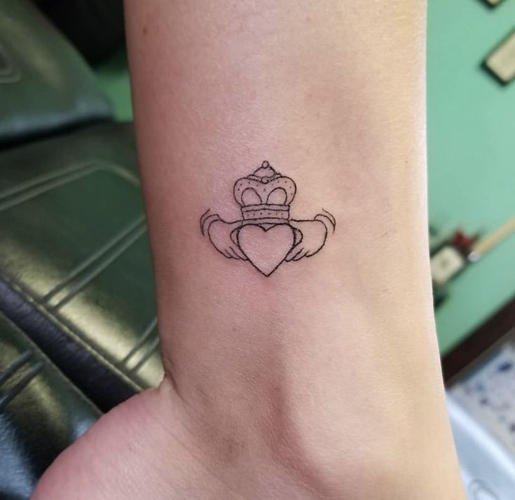 a small heart with a crown tattoo on the ankle, and an arrow in the shape of a heart