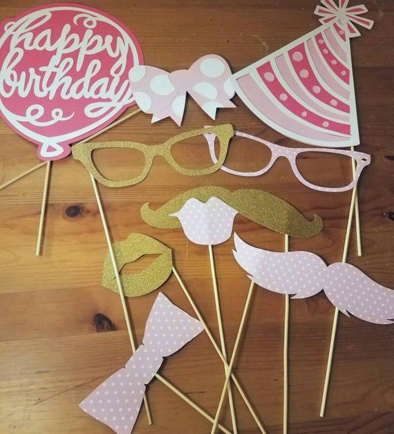 some pink and gold party decorations on a wooden table