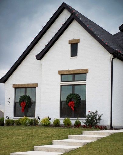 a white house with two wreaths on the windows and steps leading up to it