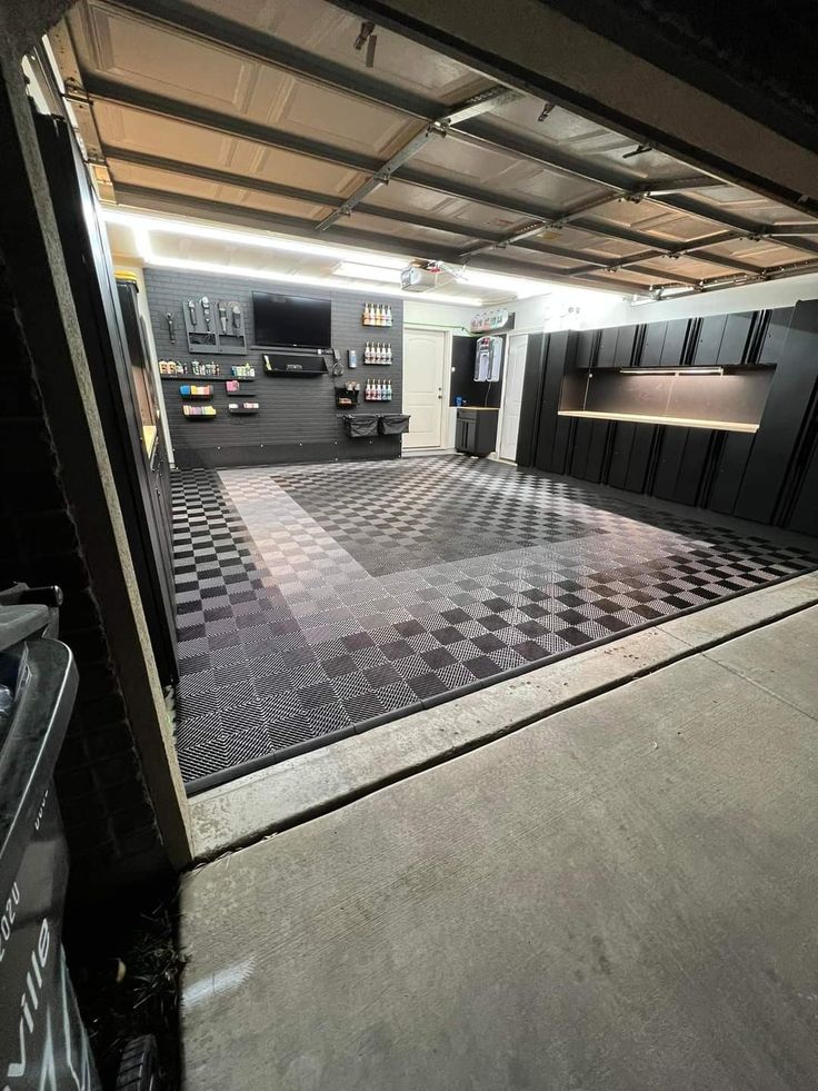 an empty garage with black and white checkered flooring on the outside, and lots of cabinets in the background