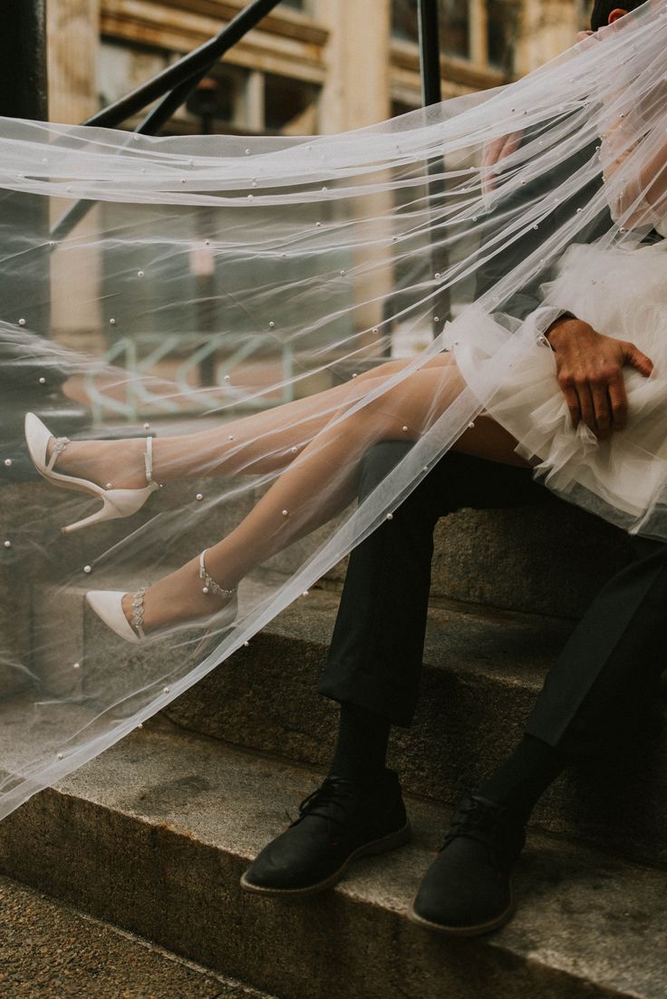 a man and woman are sitting on the steps under a veil that is covering them