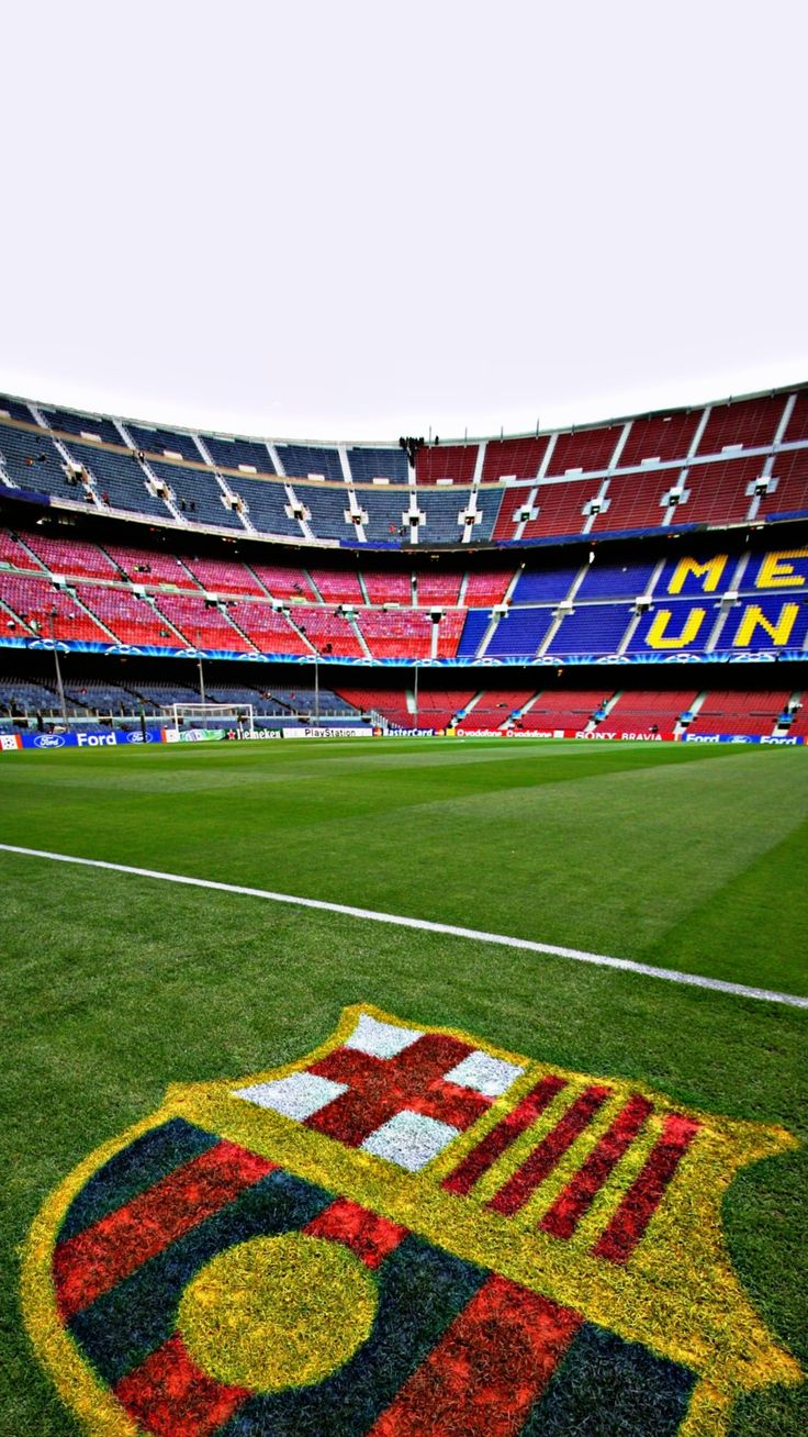 an empty soccer field with the emblem of barcelona on it's grass and stadium seats in the background