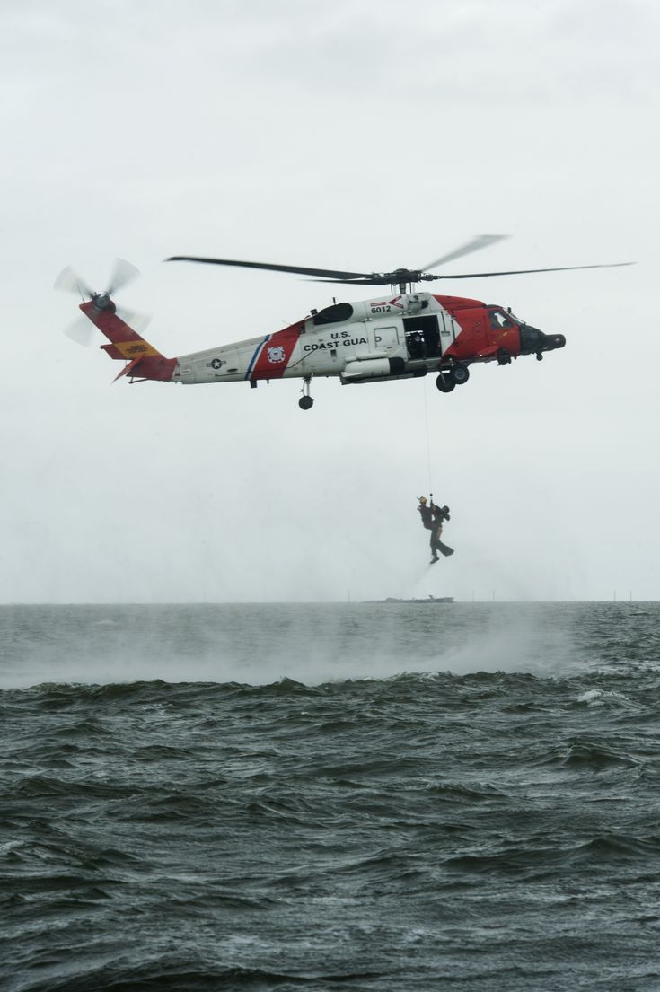 a helicopter flying over the ocean with a parasailer attached to it's back