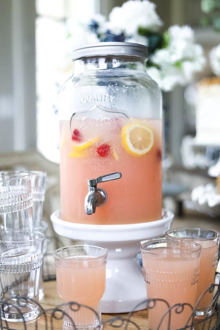 a pitcher filled with pink lemonade sitting on top of a table next to glasses