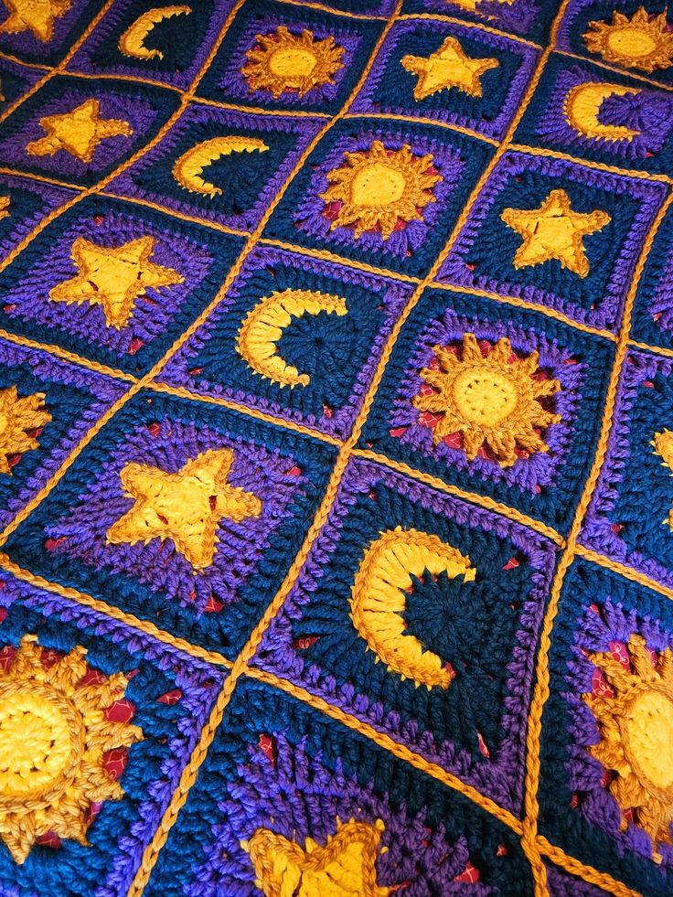 a crocheted blanket with sun, moon and stars on it