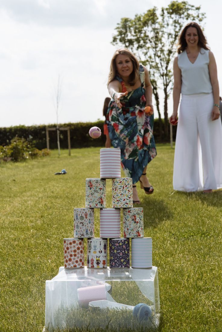 two women standing in the grass with cups stacked on top of each other