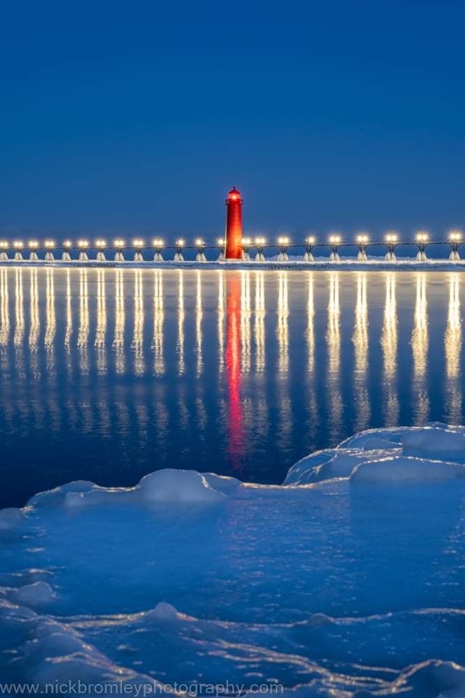 an orange light house sitting in the middle of water with ice floes around it