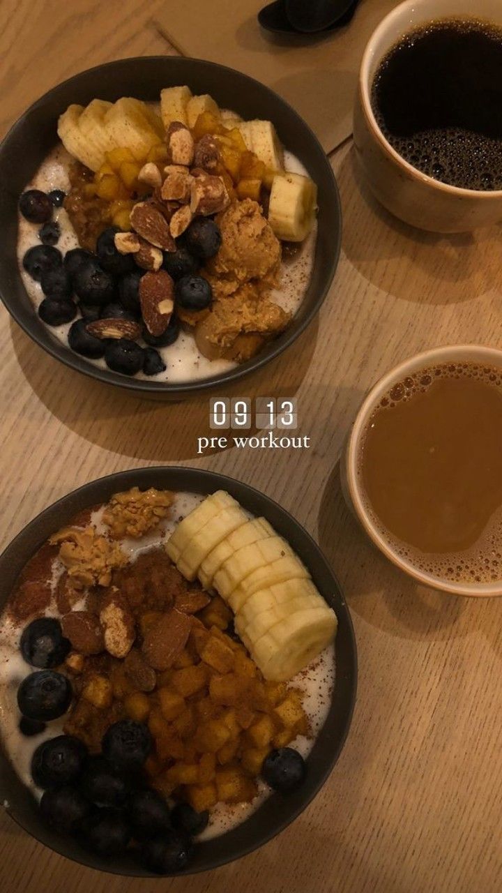 two bowls filled with cereal and fruit next to cups of coffee on a wooden table