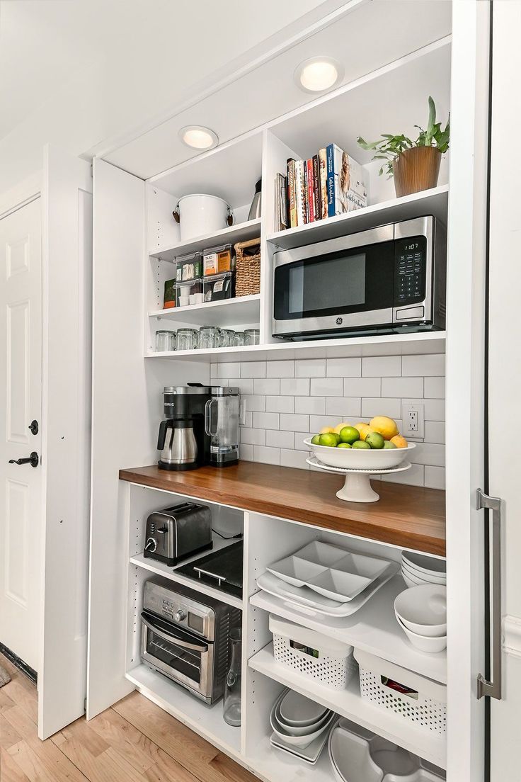 a kitchen with white cabinets and wooden counter tops, filled with plates and bowls on the shelves