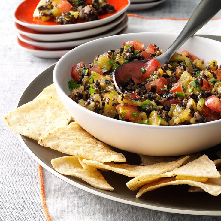 a white bowl filled with salsa and tortilla chips on top of a plate