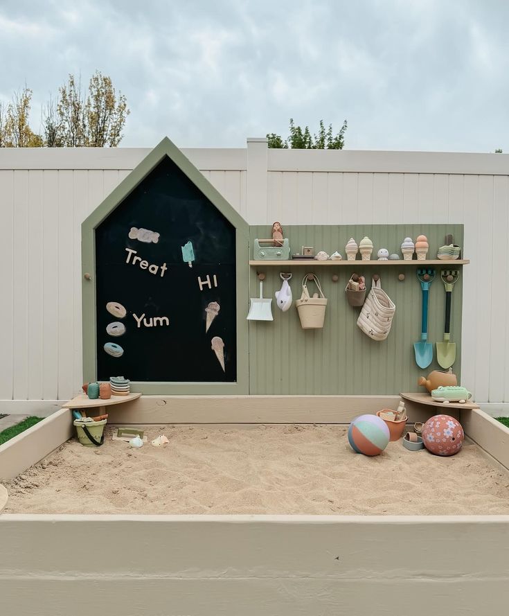 there is a sandbox with toys in it and a chalkboard on the wall