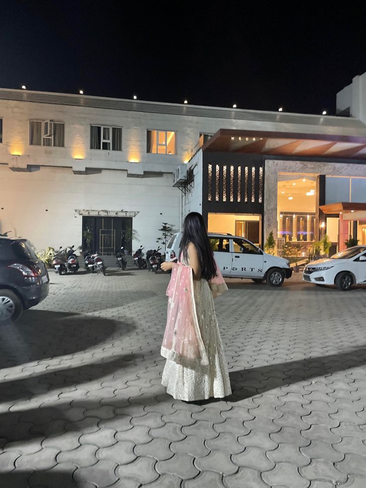 a woman is standing in front of a hotel at night with her back to the camera