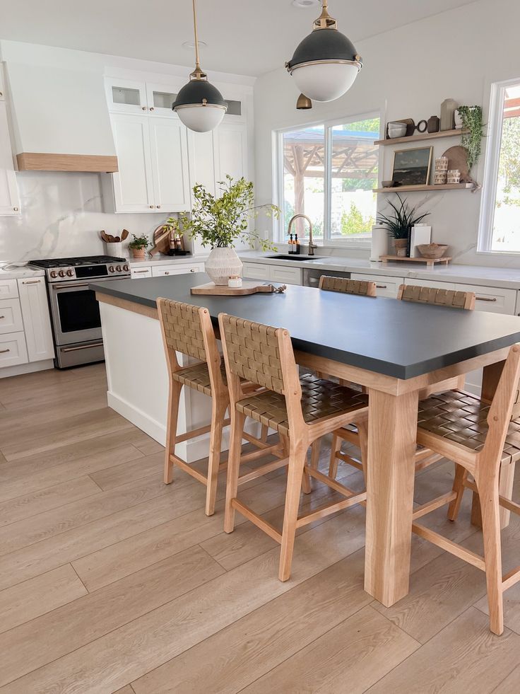 a kitchen with an island table surrounded by chairs