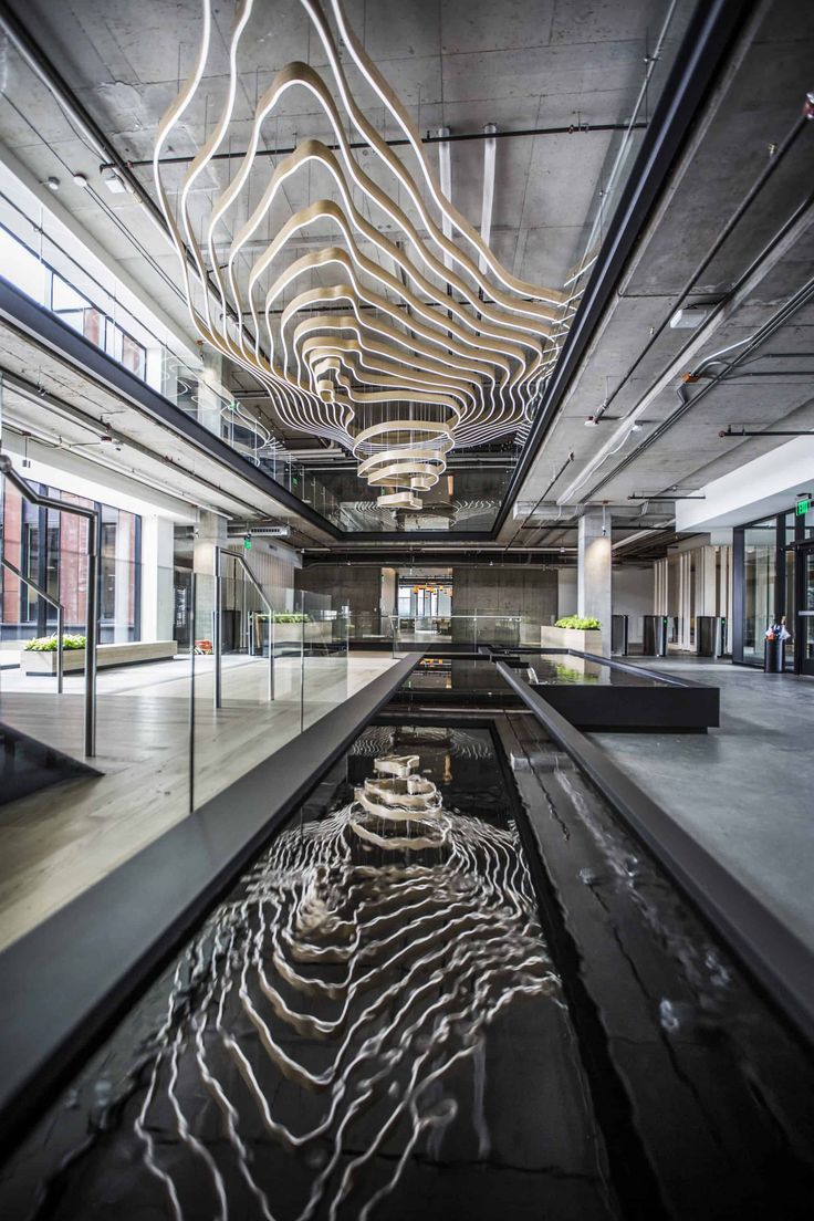 the inside of an office building with water running down it's floor and lights hanging from the ceiling