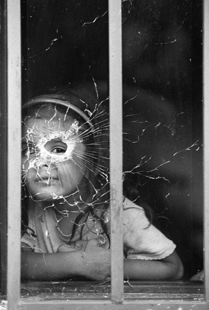 a child looking through a broken glass window